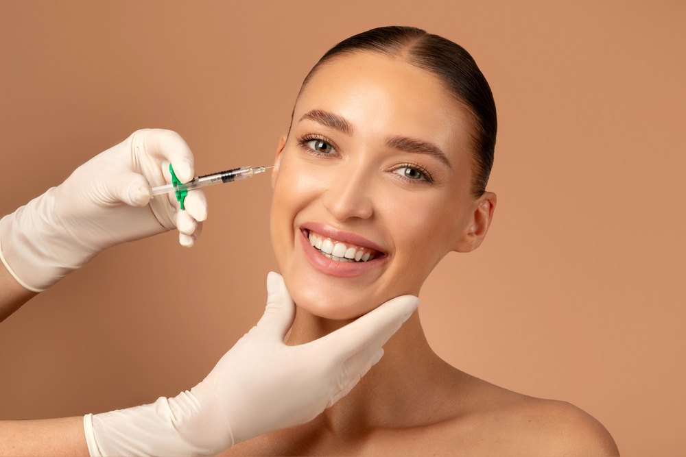 a lady smiling at the camera with a needle ready to inject to her face